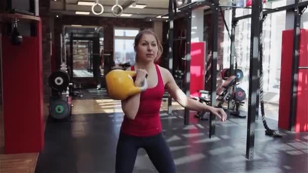 Kettlebell fitness, fiatal női sportoló csinál erőt gyakorol az edzőteremben — Stock videók