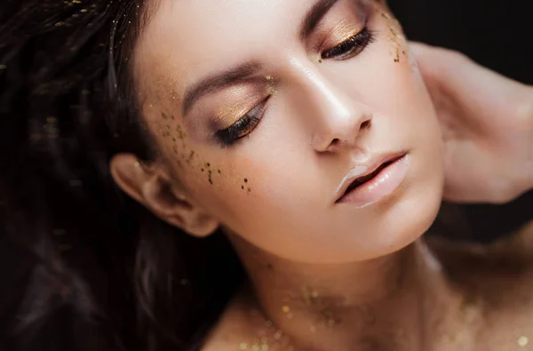 Charmant meisje met trendy glitter make-up, modieuze make-up met gouden glitter op de jukbeenderen en in de buurt van de ogen. — Stockfoto