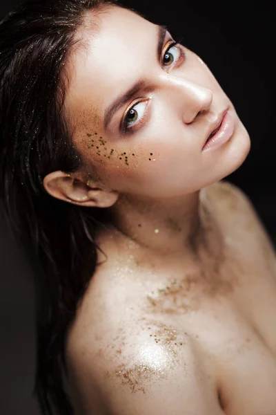 Charmant meisje met trendy glitter make-up, modieuze make-up met gouden glitter op de jukbeenderen en in de buurt van de ogen. — Stockfoto