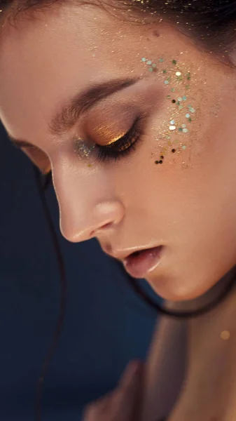 Charming girl with trendy glitter makeup, fashionable make-up with gold glitter on the cheekbones and near the eyes. — Stock Photo, Image