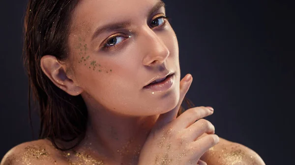 Charmant meisje met trendy glitter make-up, modieuze make-up met gouden glitter op de jukbeenderen en in de buurt van de ogen. — Stockfoto