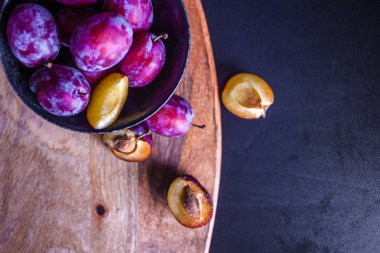 Masada bir kase lezzetli sulu mavi erik, dokulu ahşap masa,