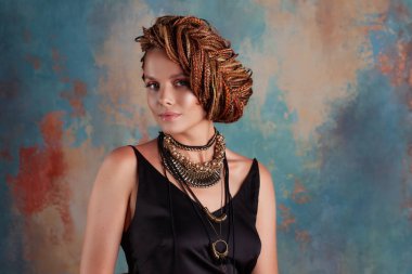 Güney baharatları. Dokulu rustik tarzı duvara karşı afrocos ve büyük süsler ile güzel bir genç mavi gözlü kadın .