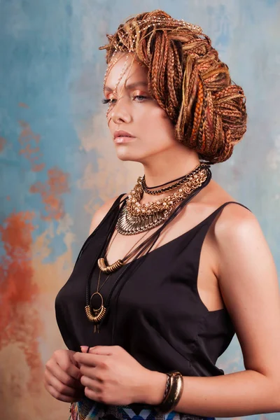 Southern flavor. Portrait of a luxurious tanned woman, pensive, stylish, with an exotic hairstyle and large jewels. — Stock Photo, Image