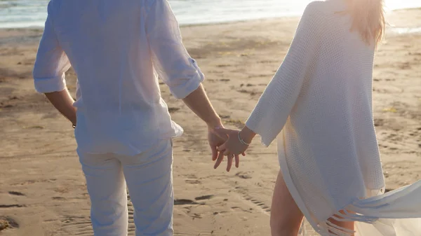 Liefde, romantiek op het strand. Jong mooi paar, vrouw, man, in witte losse vliegende kleren, lopen, langs de kust. — Stockfoto