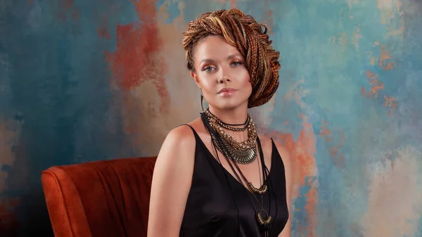 Dél-ízét. Stílusos szép fiatal nő afro zsinórra felhúzott a magas haj, székben ülve, meleg színek. — Stock Fotó
