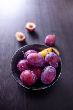 Masada bir kase lezzetli sulu mavi erik,