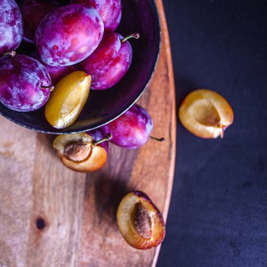 Masada bir kase lezzetli sulu mavi erik, dokulu ahşap masa,