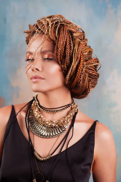 Southern flavor. Portrait of a luxurious tanned woman, pensive, stylish, with an exotic hairstyle and large jewels. — Stock Photo, Image