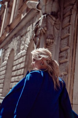 Tarihi merkezden yürüyün. Güzel bir kız, tarihi binaların arka plan karşı mavi bir ceket, boyunca yol açar.