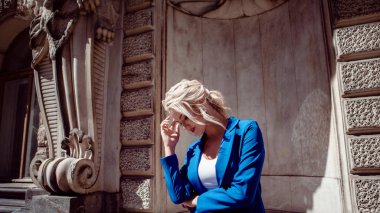 Tarihi merkezden yürüyün. Güzel kız, mavi bir pantsuit bir at kuyruğu ile sarışın, tarihi binalara karşı.