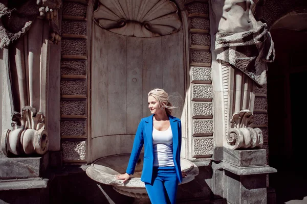 Spacer po zabytkowym centrum miasta. Piękna dziewczyna, Blondynka z kucyk w niebieskim pantsuit, przed budynkami historycznymi. — Zdjęcie stockowe