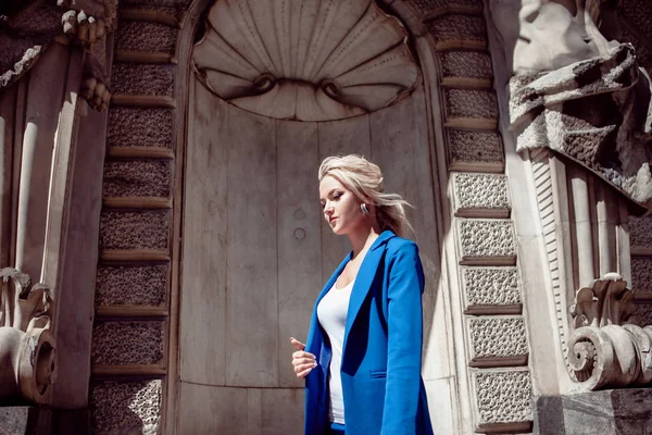 Прогулянка історичним центром. Красива дівчина, блондинка з хвостом у блакитному костюмі, проти історичних будівель . — стокове фото