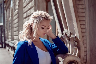 Tarihi merkezden yürüyün. Güzel kız, mavi bir pantsuit bir at kuyruğu ile sarışın, tarihi binalara karşı.