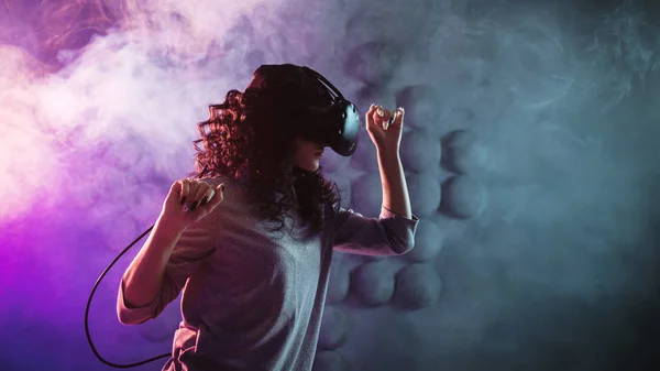 Jogo de realidade virtual. Uma menina em um capacete de realidade virtual joga um jogo ou explora o ambiente . — Fotografia de Stock