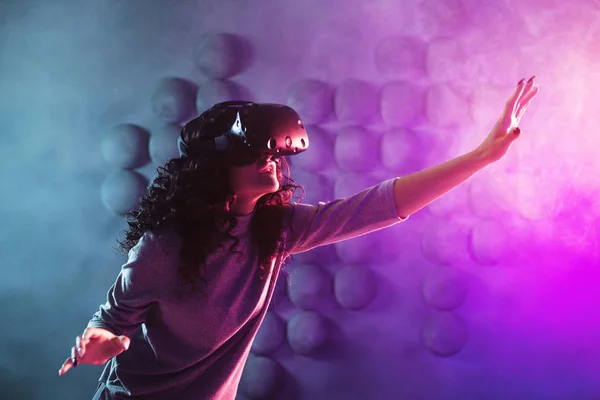 Jugador en realidad virtual, una chica juega un juego o explora el entorno en una simulación . — Foto de Stock