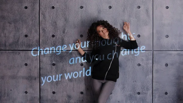 Mulher encaracolada posando ativamente em um fundo de parede com sinal de luz colorida Mude seus pensamentos e você muda seu mundo . — Fotografia de Stock