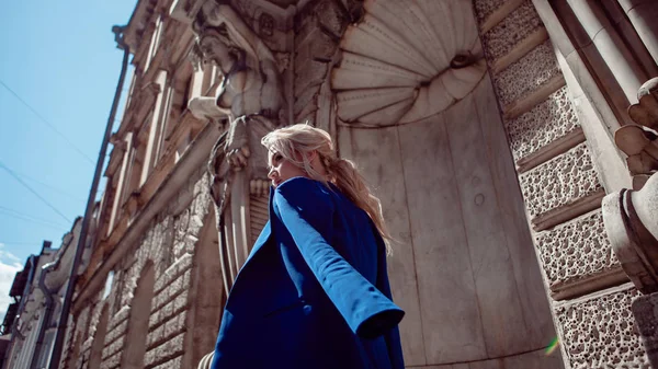 Прогулка по историческому центру. Красивая девушка, в синей куртке на фоне исторических зданий, ведет вдоль . — стоковое фото