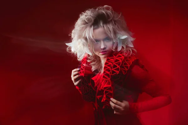 Tons de vermelho. Retrato de mulher atraente Bizar, com maquiagem de moda, em roupa de fantasia, posando em um fundo vermelho . — Fotografia de Stock