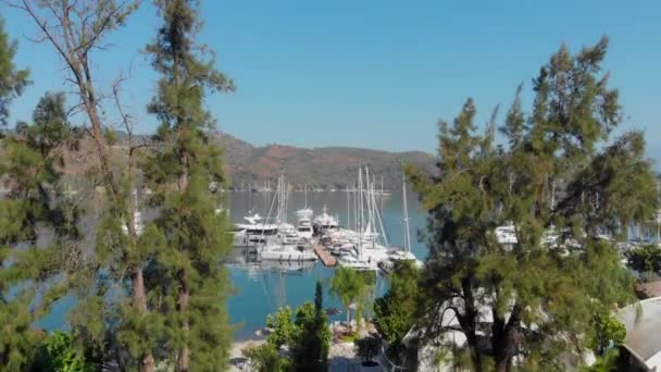 Marina och brygga med båtar, kuststad på stranden, hotell och pooler. — Stockvideo