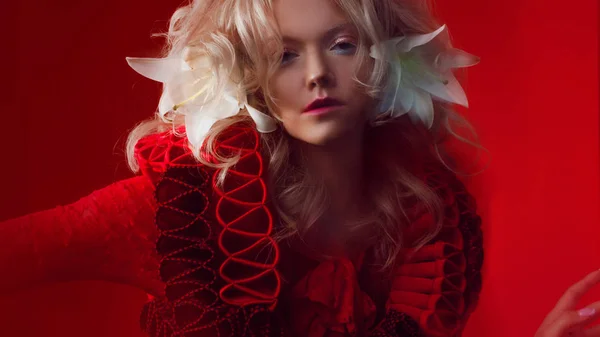 Des nuances de rouge. Portrait de Bizar femme séduisante, avec maquillage de mode, en tenue fantaisie, posant sur un fond rouge . — Photo