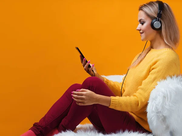 Feliz y alegre amante de la música rubia en los auriculares disfruta de la música y utiliza la aplicación de música en el teléfono inteligente —  Fotos de Stock