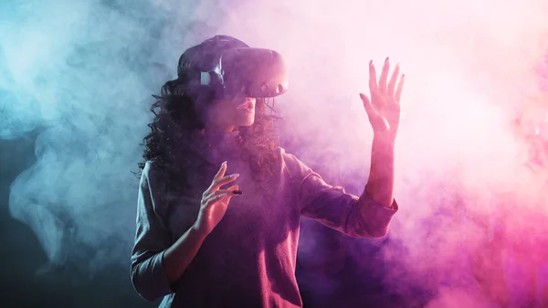 Juego de realidad virtual. Una chica en un casco de realidad virtual juega un juego o explora el medio ambiente . — Foto de Stock