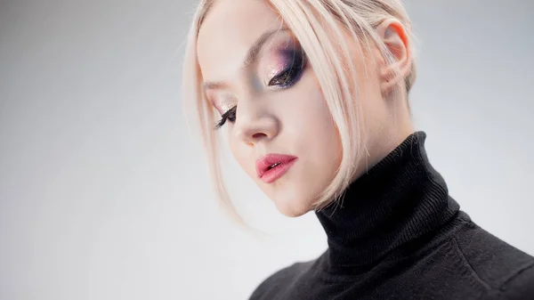 Portret van een stijlvolle strikte blonde in een zwarte coltrui met stijlvolle oogmake-up, — Stockfoto