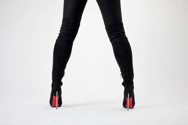 Legs wide apart in stiletto boots, back view.