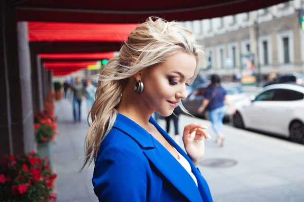 Op zoek naar koffie. Portret van mooie jonge vrouw, blonde op de achtergrond van rode venster marsen van restaurants. — Stockfoto