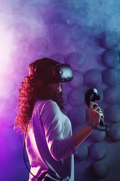 Gamer em realidade virtual, uma menina joga um jogo ou explora o ambiente em uma simulação . — Fotografia de Stock