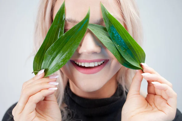 Natuurlijke cosmetica, concept. Charmant blond maakt de bloemblaadjes van de plant in de ogen, — Stockfoto