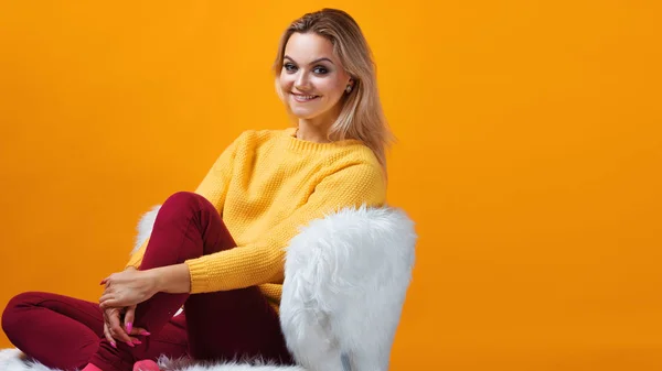 Happy and cheerful blonde in a yellow sweater on a yellow background. Positive young woman — Stockfoto