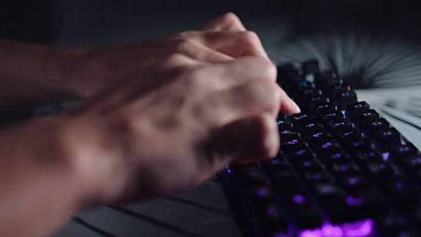 Programador escribiendo código en un teclado retroiluminado en una habitación oscura, trabajo apasionado en la computadora . — Vídeos de Stock