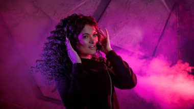 Büyük kulaklıklı güzel, kıvırcık kadın gülümser, müzik dinler, şarkı söyler, dans eder, zıplar, gözlerini kapatır..