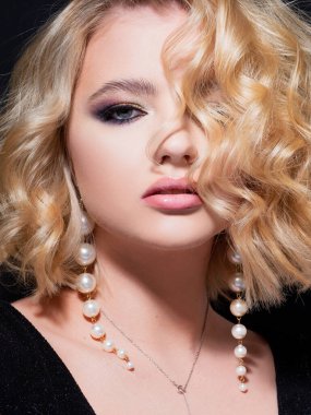 Siyah arka planda portresi olan güzel bir sarışın. Güzel genç kız, kutlama için makyaj..