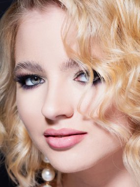 Siyah arka planda portresi olan güzel bir sarışın. Şık, seksi makyajlı güzel bir genç kız.,