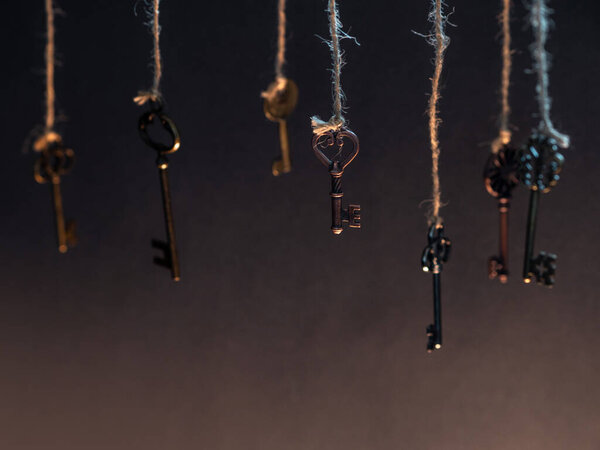 A lot of different old keys from different locks, hanging from the top on strings.