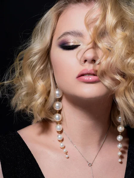 Siyah arka planda portresi olan güzel bir sarışın. Güzel genç kız, kutlama için makyaj..