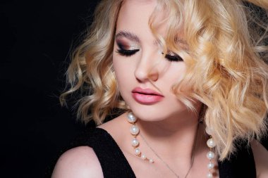 Siyah arka planda portresi olan güzel bir sarışın. Güzel genç kız, kutlama için makyaj..