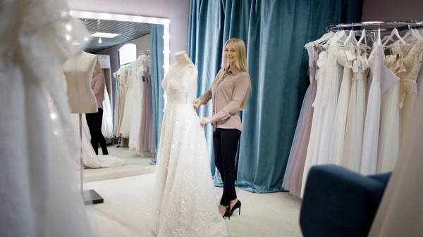 Hôtesse du salon de mariage regarde la robe de mariée. Petites entreprises, — Photo