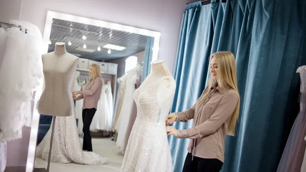 Die Wirtin des Hochzeitssalons betrachtet das Brautkleid. Kleinunternehmen, — Stockfoto