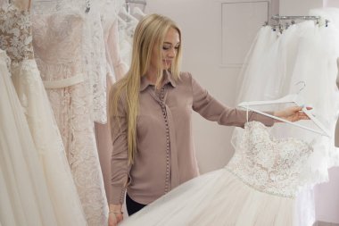 Düğün salonunun hostesi gelinliğe bakıyor. Küçük işletme,