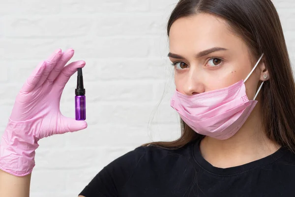 Young girl cosmetologist and brow specialist in a mask and protective gloves,