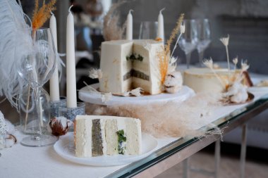 Kremalı ve kivili güzel bir düğün pastası, masa düzenleme ve tabakta bir dilim pasta..