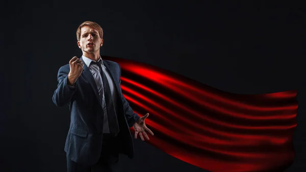 Superhrdina v červeném plášti pronese vzrušující projev, mladý muž v obleku a kravatě pronese inspirující projev. — Stock fotografie