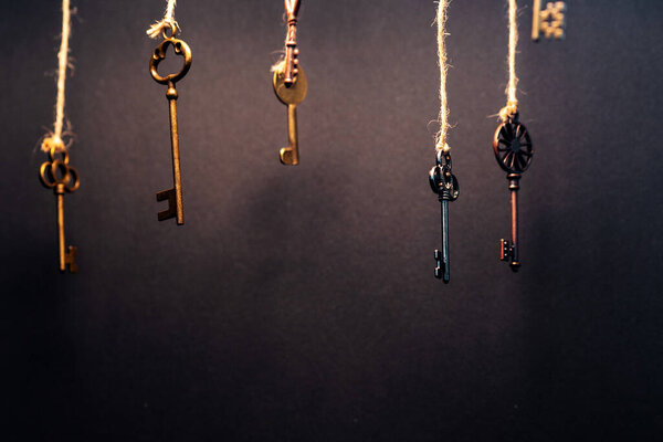 A lot of different old keys from different locks, hanging from the top on strings.