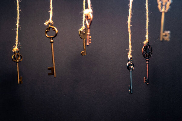 A lot of different old keys from different locks, hanging from the top on strings.