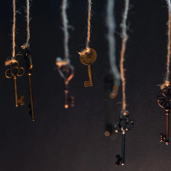 Beaucoup de vieilles clés différentes de serrures différentes, suspendues du haut sur des cordes. — Photo
