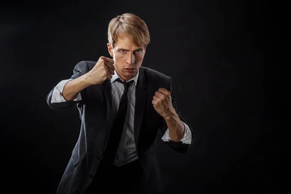 Competition in business, concept. A young man in a suit and tie fights with his fists, Stock Picture